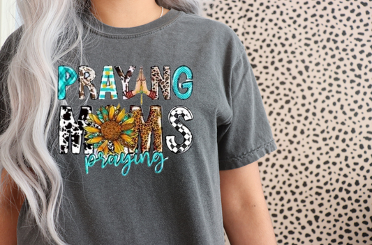 Gray t-shirt with colorful 'Praying Moms' design on a patterned background